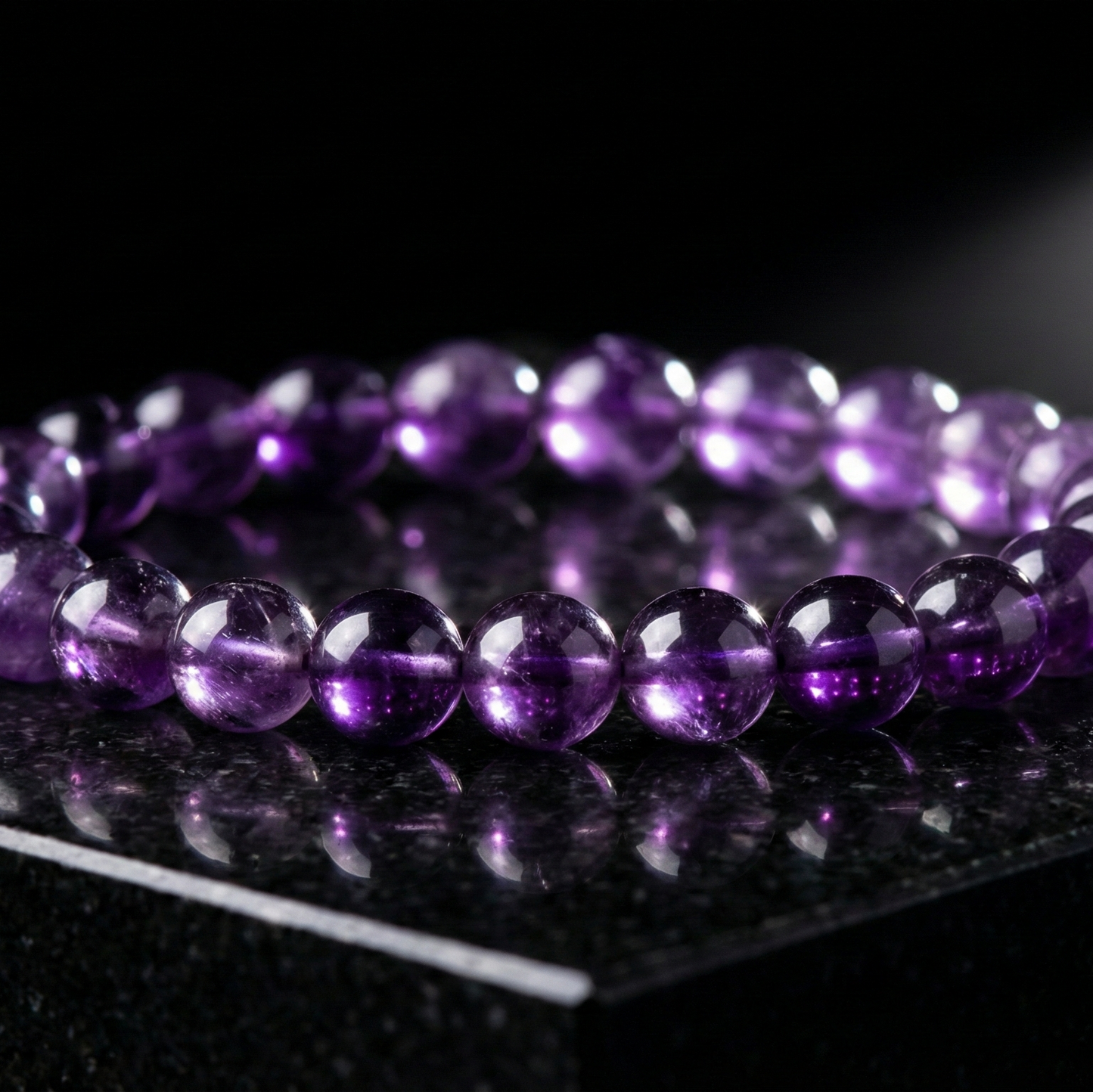 Purple beaded bracelet on a reflective black surface with a spotlight effect