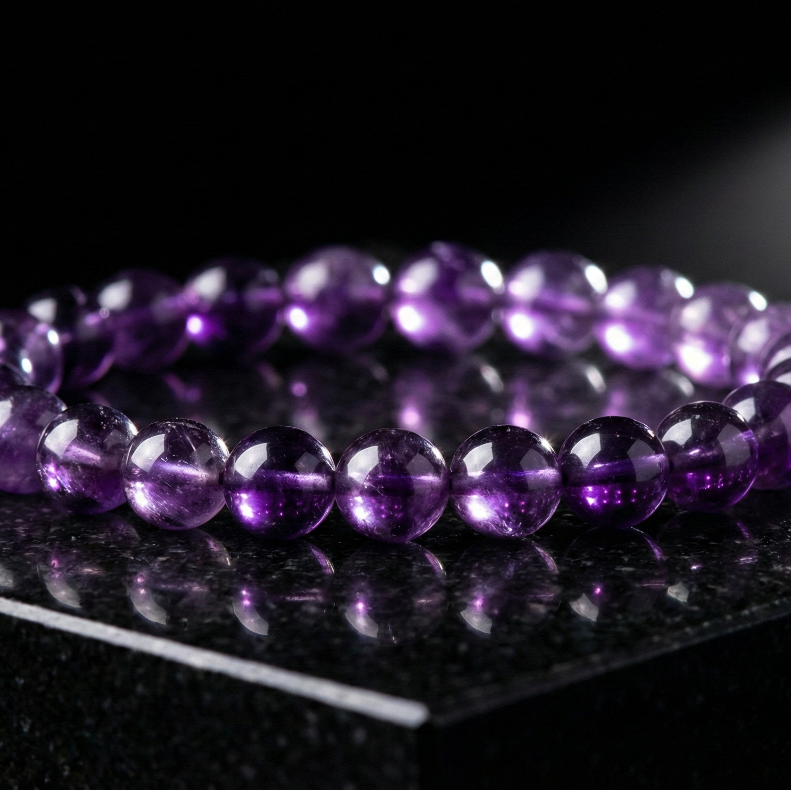 Purple beaded bracelet on a reflective black surface with a spotlight effect